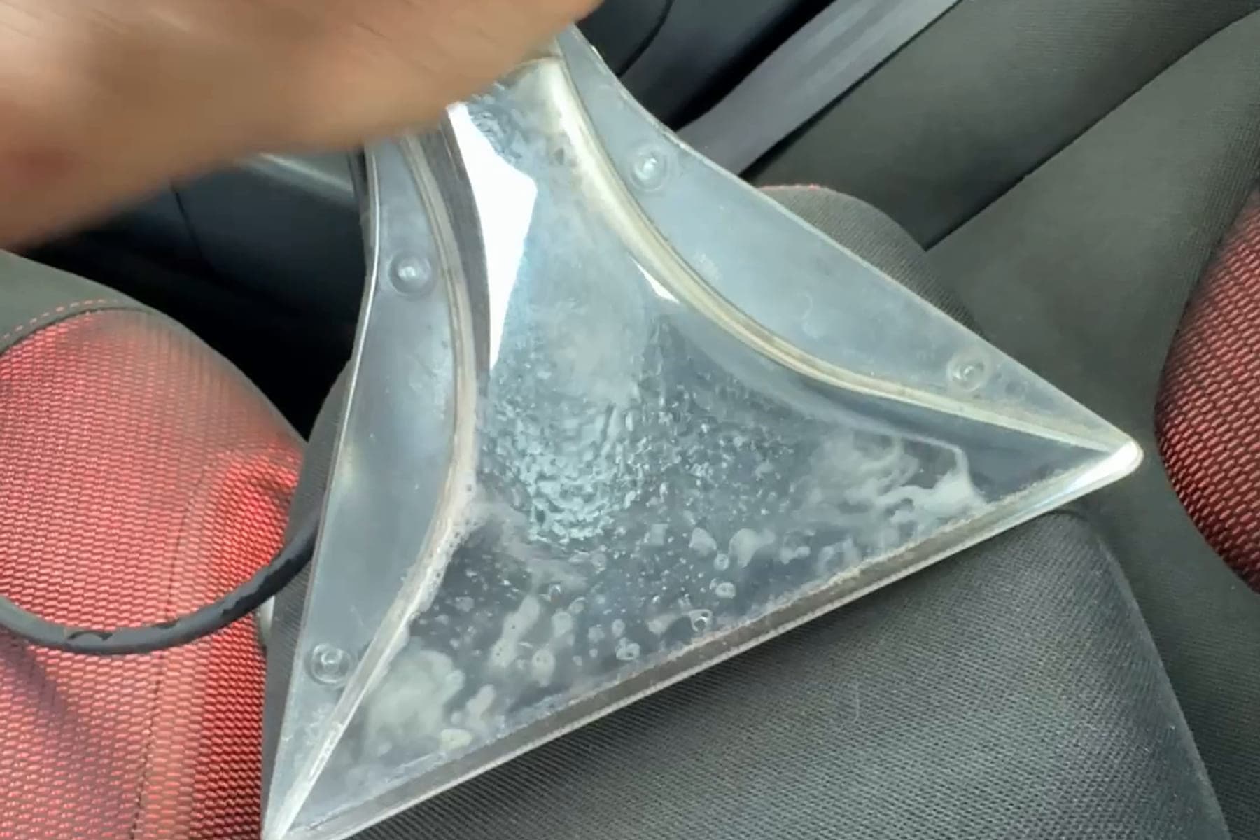 Suceur transparent d'injection-extraction sur un siège, la saleté visible à l'intérieur